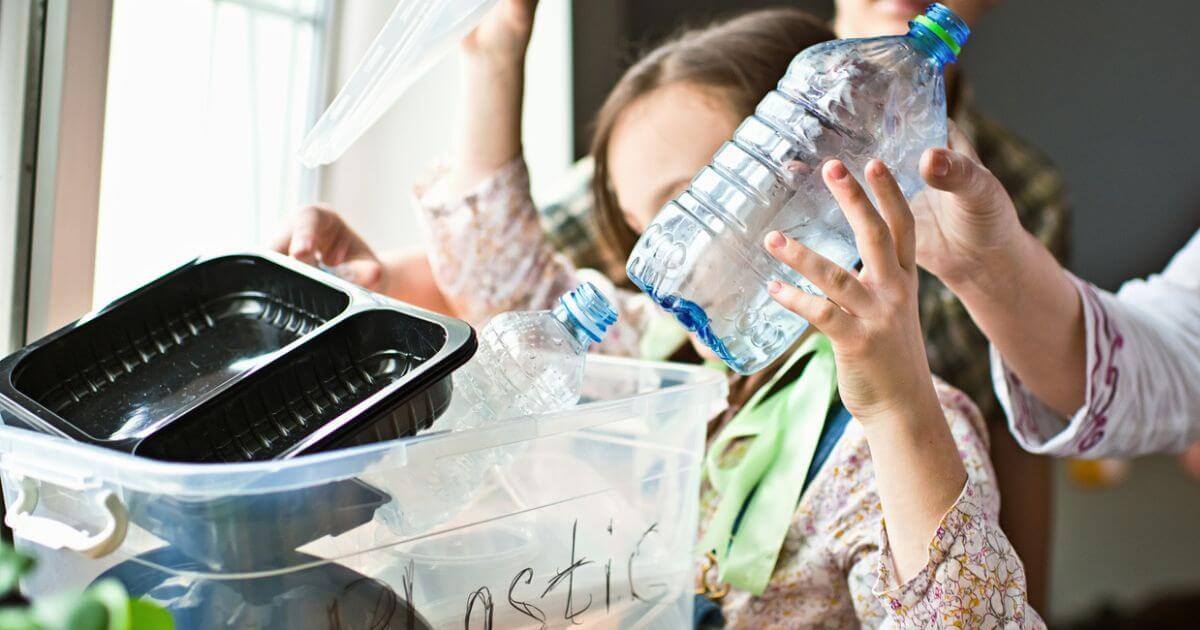 Children putting plastic pottles into a recycling bin