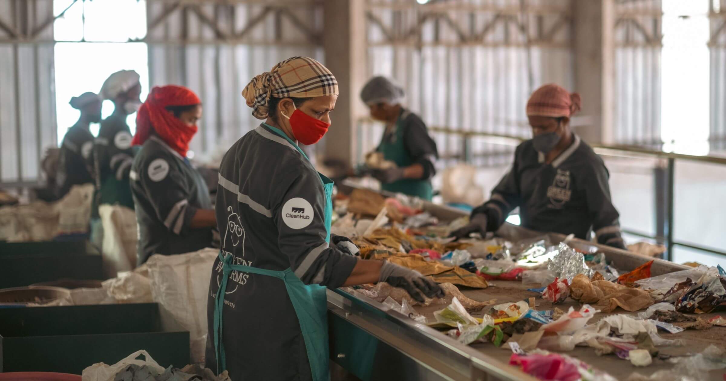 People working on the  conveyer belt at a waste collection facility sorting plastic