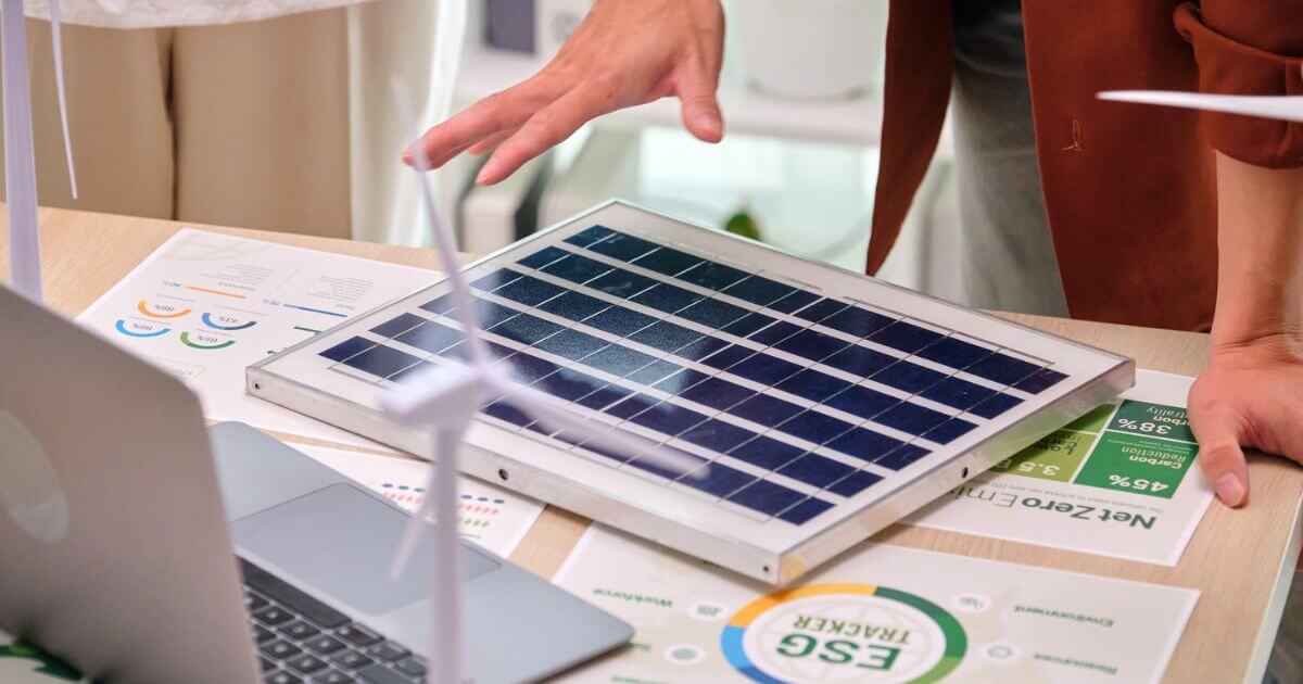 An ESG plan and miniature solar panels laid out on a table with someone leaning over it