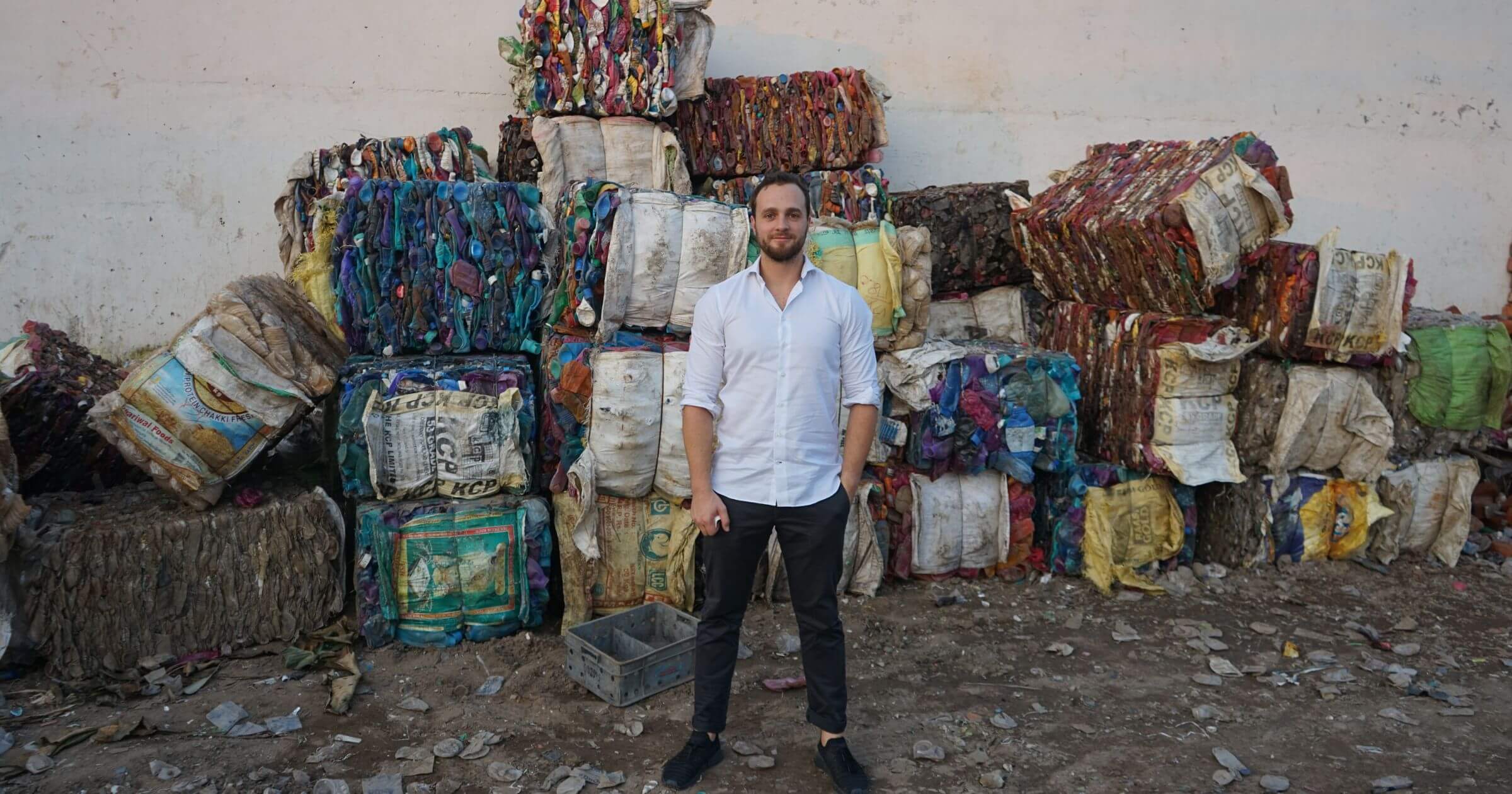 Joel Tasche, co-founder of CleanHub, stands in front of piles of collected plastic