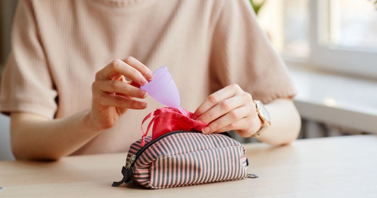Someone putting a small pink menstrual cup in a bag
