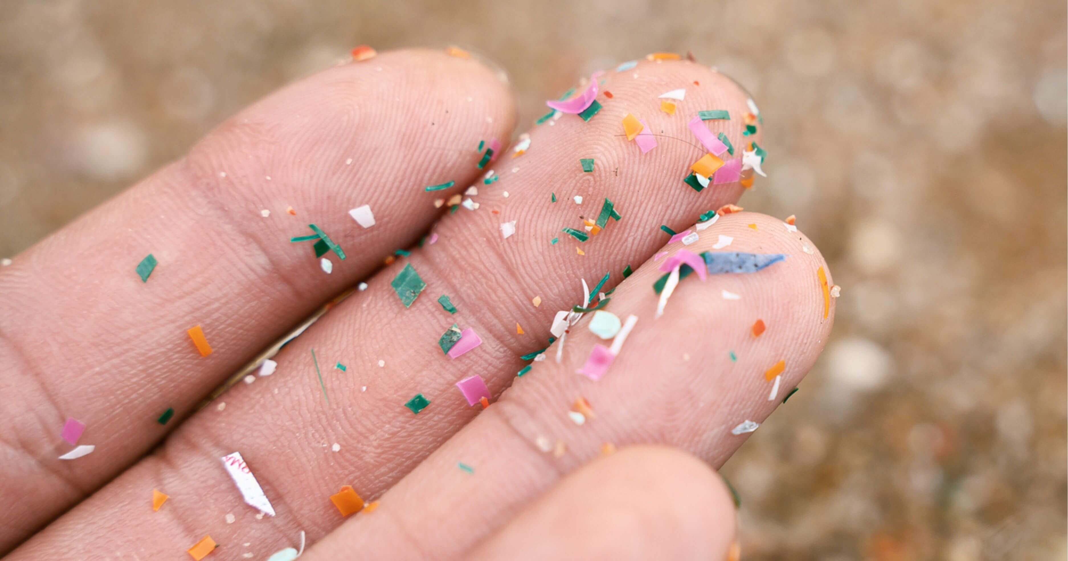 Tiny fragments of colourful plastic on someones fingers 