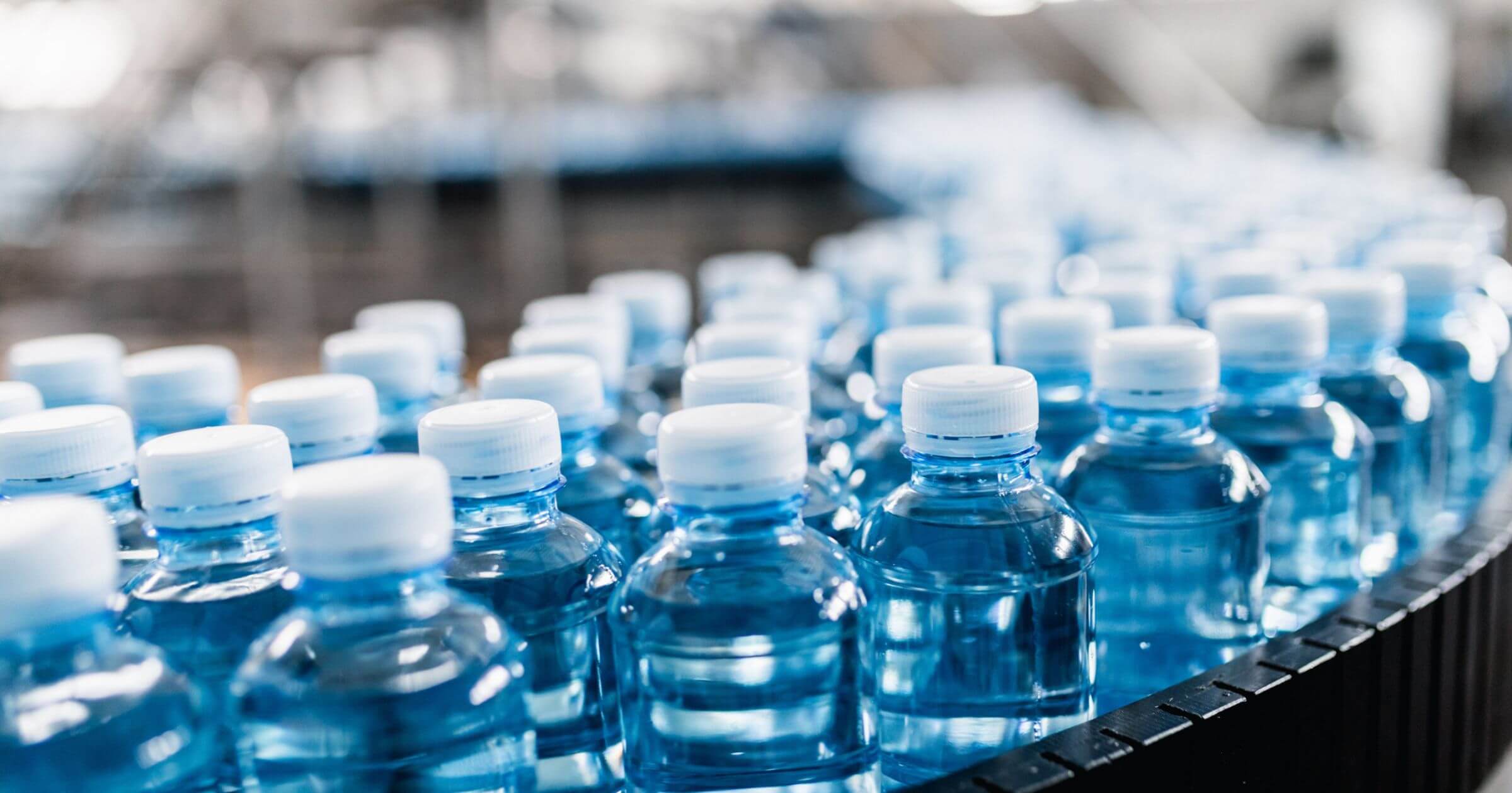 rows of plastic water bottles on a conveyer belt