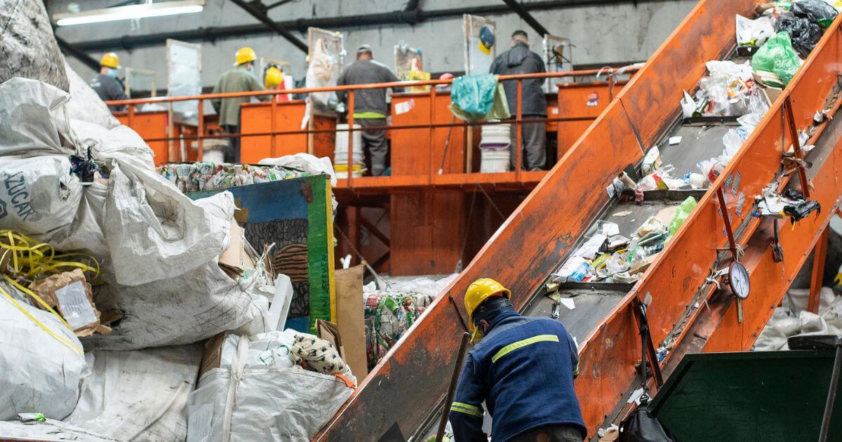 Someone putting trash on a conveyor belt at a recycling facility 